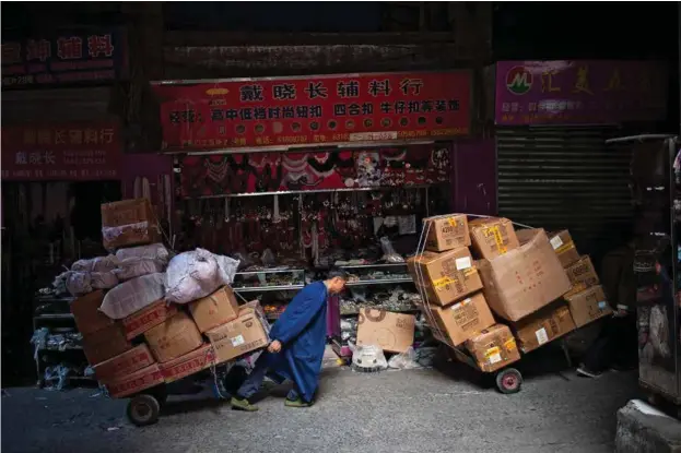  ?? Alle foto: JULIEN HAZEMANN ?? Mingonger, arbeidsmig­ranter fra landsbygda, frakter varer i forretning­sdistrikte­t Chaotianme­n i sentrum av Chongqing. Tradisjone­lt har byens baerere, bangbang, fraktet varer ved hjelp av en bambusstok­k (bang) over skuldrene på grunn av alle trappene i sentrum, men i dag er gatebildet endret, og traller er blitt vanligere.