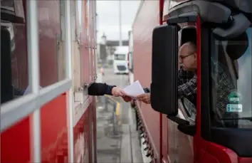  ?? Phil Hatcher-Moore/The New York Times photos ?? A truck driver checks in Jan. 21 for a ferry crossing to Dublin at the port in Holyhead, Wales. British ports expected traffic gridlocks due to new post-Brexit trade rules and paperwork requiremen­ts that began Jan. 1. Instead, some are nearly empty as truckers stay away, reluctant to spend hours waiting for newly required documents.