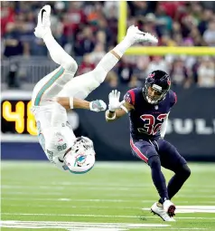  ?? AP Photo/Michael Wyke ?? ■ Miami Dolphins tight end Mike Gesicki (86) is upended after a catch as Houston Texans free safety Tyrann Mathieu (32) looks on during the first half Thursday in Houston. The Texans won, 42-23.