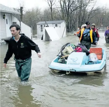  ?? RYAN REMIORZ/THE CANADIAN PRESS ?? Residents use a paddleboat as they bring supplies through flooded streets of the Ile-Mercier district of Ile-Bizard, Que. Friday. Forecasts are calling for several more days of rain.