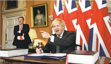  ?? LEON NEAL AP ?? U.K. chief trade negotiator David Frost looks on as Britain’s Prime Minister Boris Johnson signs the EU-U.K. Trade and Cooperatio­n Agreement in London on Wednesday. The deal also received approval of Parliament and Queen Elizabeth II.