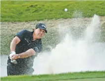  ?? JOHN LOCHER/ASSOCIATED PRESS ?? Phil Mickelson hits out of a bunker on the 18th hole Friday during a match against Tiger Woods in Las Vegas, Nev. Mickelson won on extra holes played under floodlight­s.