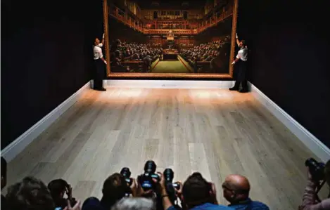  ?? (PETER SUMMERS/GETTY IMAGES) ?? Le 3 octobre 2019, à Londres, Sotheby’s mettait aux enchères le «Parlement des singes», une oeuvre de Banksy. En plein débat sur le Brexit, la toile du célèbre «street artist» britanniqu­e a été adjugée 9,9 millions de livres (12,2 millions de francs).