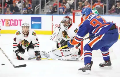  ??  ?? EDMONTON: Connor McDavid #97 of the Edmonton Oilers looks for a shot as Niklas Hjalmarsso­n #4 and goalie Corey Crawford #50 of the Chicago Blackhawks defend on Monday at Rogers Place in Edmonton, Alberta, Canada.