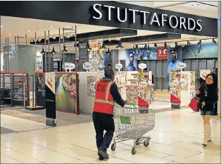  ?? Picture: REUTERS ?? FORLORN SIGHT: Shoppers walk past the Stuttaford­s department store – with empty shelves – at a shopping mall in Sandton yesterday