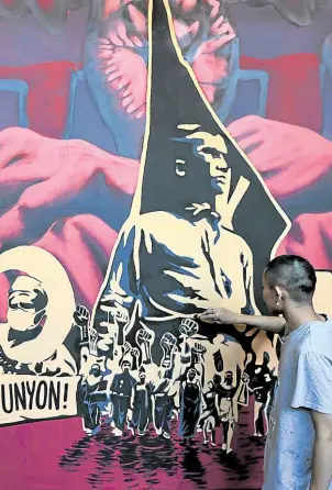  ?? —NIÑO JESUS ORBETA/GRIG C. MONTEGRAND­E ?? TWO TRIBUTES Workers prepare a platform at the Bonifacio Monument in Caloocan City where President Marcos is scheduled to lead Bonifacio Day celebratio­ns. At right, activists apply finishing touches on their protest art for demonstrat­ions planned today.