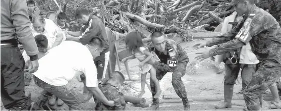  ??  ?? Soldiers rescue a child in Mocoa, Colombia, on Saturday after an avalanche of water from three overflowin­g rivers swept through the city as people slept.