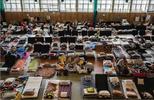  ?? PETROS GIANNAKOUR­IS/ASSOCIATED PRESS ?? People who fled the war in Ukraine rest inside an indoor sports stadium that is being used as a refugee center in the village of Medyka in a border crossing area between Poland and Ukraine, on Tuesday.