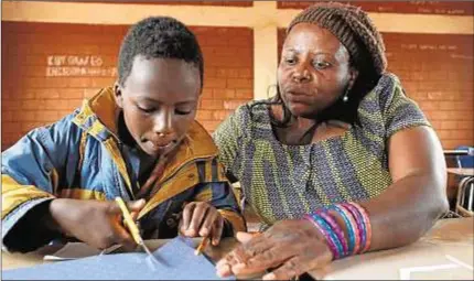  ?? Entrecultu­ras ?? Sanganyi Namangala ayuda a un alumno del colegio del campo de refugiados a hacer su dibujo