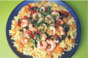  ??  ?? Couscous is tossed with diced butternut squash and fresh chives as a bed for Moroccan spiced shrimp. You can stock all the ingredient­s in advance.