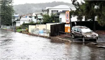  ?? — AFP photo ?? Houses are seen on the bank of overflowin­g Woronora river, as inclement weather triggered evacuation orders in several suburbs of Sydney’s south and southwest.