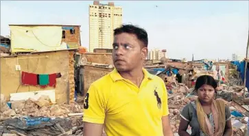  ?? Shashank Bengali Los Angeles Times ?? SANTOSH GOND renovated his slum home with a loan from his boss. Months later, bulldozers destroyed it. Behind him is the scandal-ridden Adarsh Tower, which the Supreme Court has blocked from demolition.