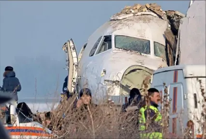  ?? Vladimir Tretyakov/Associated Press ?? Police stand guard as rescuers assist at the site of a plane crash Friday near Almaty Internatio­nal Airport outside Almaty, Kazakhstan. The Bek Air plane with 98 people aboard crashed shortly after takeoff, coming to rest with its nose into a building.