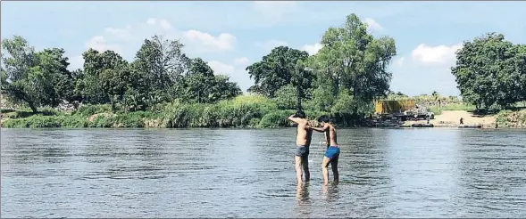  ??  ?? Temptejant l’aigua. Dos salvadoren­cs inspeccion­en el riu que hauran de travessar per arribar a Mèxic