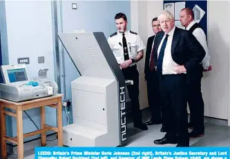  ??  ?? LEEDS: Britain’s Prime Minister Boris Johnson (2nd right), Britain’s Justice Secretary and Lord Chancellor Robert Buckland (2nd left), and Governor of HMP Leeds Steve Robson (right), are shown a torso and body scanner by a member of prison staff during a visit to HM Prison Leeds. —AFP