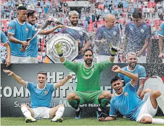  ?? KIRSTY WIGGLESWOR­TH THE ASSOCIATED PRESS ?? Manchester City's players celebrate with the trophy after the English Community Shield soccer match between Liverpool and Manchester City at Wembley stadium in London, Sunday.