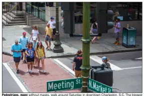  ?? (The New York Times/Gavin McIntyre) ?? Pedestrian­s, many without masks, walk around Saturday in downtown Charleston, S.C. The biggest spikes in coronaviru­s infections have been seen in the West and South.