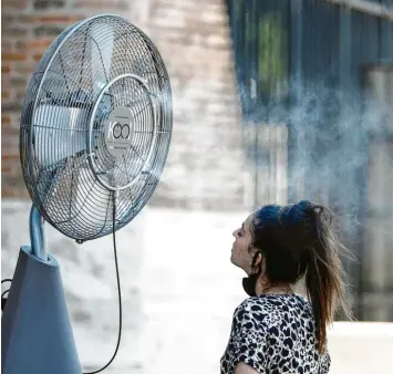  ?? Foto: Cecilia Fabiano, LaPresse/AP, dpa ?? Abkühlung tut not: Eine Frau erfrischt sich an einem Ventilator mit Wassernebe­l, der neben dem Kolosseum in Rom aufgebaut wurde. In Italien stieg das Thermomete­r auf 38 Grad Celsius und mehr.