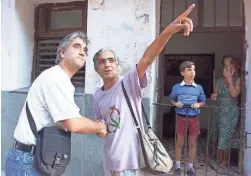  ?? ARIZONA REPUBLIC FILE PHOTO ?? Arizona Republic reporter Pedro Gomez looks up to where Evelio Hernandez points out he lives in Havana, Cuba.