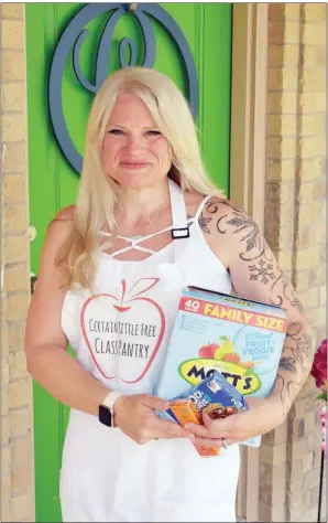  ?? STACI VANDAGRIFF/RIVER VALLEY & OZARK EDITION ?? Crystal Certain stands on her front porch and holds snacks for the Certain Little Free Class Pantry she started at Conway High School, where she teaches art. Certain said she had a couple of shelves of snacks, but that grew to half of her classroom closet. Her students named the pantry, which is sponsored in the summer by Community Action Program of Central Arkansas. “If you’re hungry, you can’t learn,” Certain said.