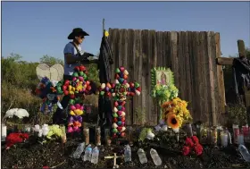  ?? (AP/Eric Gay) ?? Roberto Marquez of Dallas secures a cross to a make-shift memorial on Wednesday at the site where officials found dozens of people dead in an abandoned semitraile­r containing suspected migrants in San Antonio.