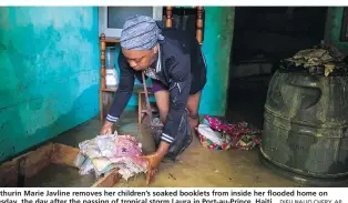  ?? DIEU NALIO CHERY, AP ?? Mathurin Marie Javline removes her children’s soaked booklets from inside her flooded home on Tuesday, the day after the passing of tropical storm Laura in Port-au-Prince, Haiti.