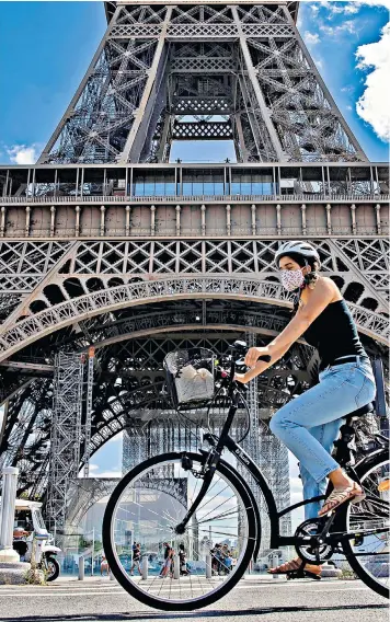  ??  ?? A woman wearing a face covering cycles near the Eiffel Tower as Paris today makes masks compulsory in all outdoor spaces. It came as France recorded a post-lockdown record of more than 6,100 new virus infections in just 24 hours and its R rate rose to 1.4.