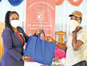  ?? PHOTO BY CARL GILCHRIST ?? President of the St Ann chapter of the Jamaica Associatio­n of Administra­tive Profession­als, Marilyn Wisdom-Garrick (left), hands over a care package to a household helper in St Ann on Wednesday, April 22.