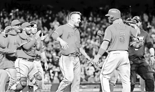  ?? ELAINE THOMPSON/AP ?? Mike Trout and friends converge to congratula­te Angels slugger Albert Pujols on his 3,000th hit.