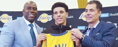  ?? AFP ?? Magic Johnson, president of basketball operations of the Los Angeles Lakers along with general manager Rob Pelinka present Lonzo Ball his jersey during a press conference at the team training facility in Los Angeles, California.