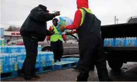  ??  ?? Workers load cars with cases of water in Flint in April 2018. Photograph: Garrett MacLean/The Guardian
