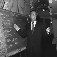  ?? ASSOCIATED PRESS FILE ?? NFL commission­er Pete Rozelle works at on a blackboard at a New York City hotel during the first round of the 1967 combined NFL and AFL draft.