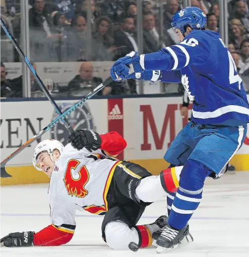  ?? CLAUS ANDERSEN/ GETTY IMAGES ?? Flames forward Curtis Lazar gets decked by Maple Leafs defenceman Roman Polak during game at Air Canada Centre on Wednesday. Despite shaky play throughout, the Leafs posted a 2-1 shootout victory.