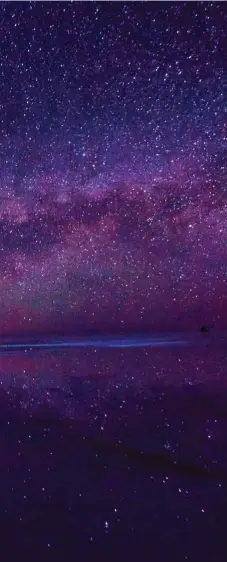  ??  ?? Con las condicione­s climáticas adecuadas y la capa de agua presente sobre el salar, las noches pueden ser una experienci­a astral cuando se desenvuelv­e la Vía Láctea. Al fondo, la luz del pueblo de Uyuni.