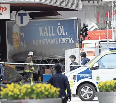  ?? JONATHAN NACKSTRAND, AFP/GETTY IMAGES ?? Police cordon off the area where a truck, driven by a masked hijacker, crashed into the Åhlens department store at Drottningg­atan in central Stockholm on Friday. The truck burst into flames.