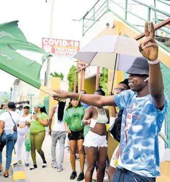  ?? GLADSTONE TAYLOR/MULTIMEDIA PHOTO EDITOR ?? A Jamaica Labour Party supporter waves a flag in the St Andrew West Central constituen­cy as he dances with fellow Jamaica Labour Party supporters in the vicinity of the Olympic Gardens Police Station.