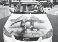  ?? AP ?? A man sits in a Russian-made sports car with a depiction of Russia’s Vladimir Putin (left) and Dmitry Medvedev.