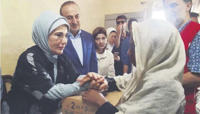  ??  ?? First Lady Emine Erdoğan, left, and Foreign Minister Mevlüt Çavu oğlu, second from left, give out aid boxes during their visit to the Kutupalong Refugee Camp, which is home to Rohingya Muslims who fled from Myanmar in Cox's Bazar, Sept. 7.