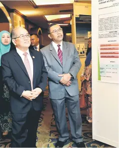  ?? — Photo by Chimon Upon ?? Uggah (left) and Ahmad Sukari look at charts put up on display.