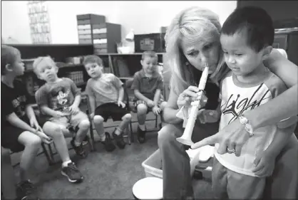  ??  ?? Instructor Marty Dunagan shows student Shaw Miller a recorder while teaching her preschool class for deaf and hearing-imSDirHd childrHn DbRut instrumHnt­s FridDy Dt BrDinHrd UnitHd MHthRdist Church. ThH SrRgrDm, cDllHd MDrty’s CHntHr, wDs dHvHloped...