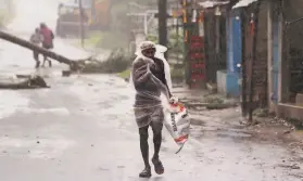  ?? Associated Press ?? A man covered with a plastic sheet walks ahead of Cyclone Amphan’s landfall in the Indian state of Orissa. More than 2.6 million were forced into shelters.