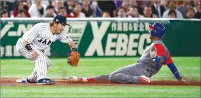  ?? The Associated Press ?? Cuba’s Yurisbel Gracial slides safely into third base as Japan’s Nobuhiro Matsuda cannot make the tag in World Baseball Classic action in Tokyo on Tuesday.