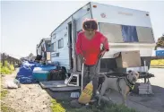  ?? Jessica Christian / The Chronicle ?? Amilee Smith, 60, cleans up the area outside of her RV with her dog Mimi while parked at an RV encampment along Rydin Road in Richmond.