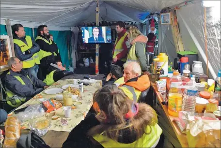  ?? Jean-Francois Monier AFP/Getty Images ?? “YELLOW VESTS” in a tent in Le Mans, France, watch Emmanuel Macron’s TV address, in which he said he understood people’s anger.