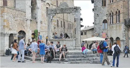  ?? CAMERON HEWITT ?? Tourists hang out at San Gimignano’s Piazza della Cisterna by a well where locals got their water 1,000 years ago.