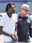  ??  ?? An alleged lottery scammer shackled and on his way to face charges in the United States.