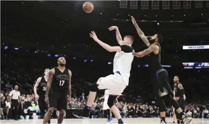  ??  ?? NEW YORK: New York Knicks forward Kristaps Porzingis, center, shoots in front of Phoenix Suns forward Markieff Morris, right, during the fourth quarter of an NBA basketball game, Friday, in New York. The Knicks won 102-84. —AP