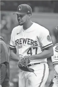  ?? MARK HOFFMAN / MILWAUKEE JOURNAL SENTINEL ?? Brewers relief pitcher Angel Perdomo heads to the dugout Monday night after it was discovered he wasn't on the lineup card for the game against the Cubs.