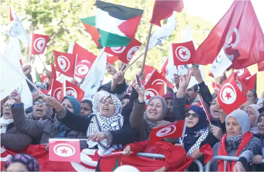  ??  ?? People wave national flags during demonstrat­ions on the seventh anniversar­y of the toppling of President Zine El-Abidine Ben Ali, in Tunis on Sunday. (Reuters)