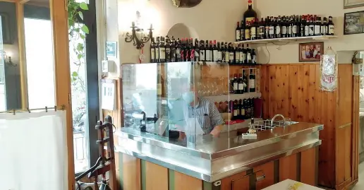  ??  ?? Sopra il grande divisorio in plexiglass messo alla cassa della trattoria Da sinistra: il cameriere che versa l’olio e il formaggio agli unici clienti che hanno voluto sedersi allo stesso tavolo